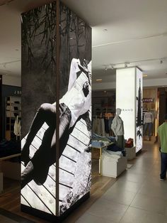 a man is walking through a mall with an advertisement on the wall