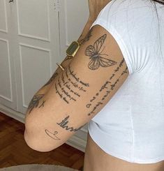 a woman with a butterfly tattoo on her arm and chest is standing in front of a mirror