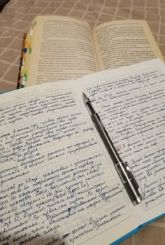 an open notebook with writing on it and a pen resting on the book's page