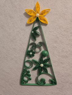 a green and yellow christmas tree decoration on a white surface with flowers in the center