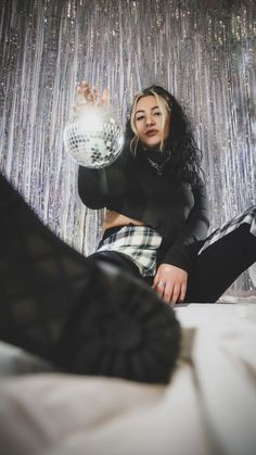 a young woman sitting on top of a bed next to a disco ball wallpaper