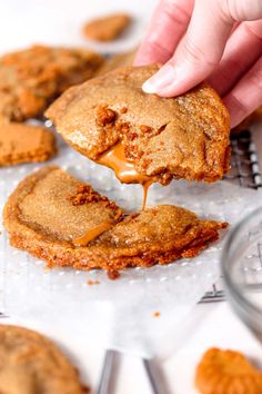 a person dipping some kind of cookie into the batter on top of cookies that have been cut in half