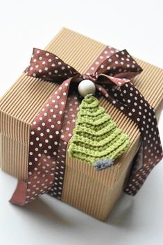 a small christmas tree wrapped in brown and white paper with polka dots on the ribbon