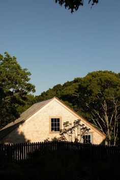 a house with a fence and trees in the background