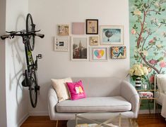 a white couch sitting in a living room next to a wall with pictures on it