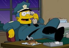 the simpsons is laying on his stomach in front of a desk with food and drinks