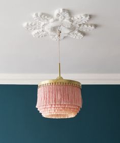 a pink chandelier hanging from the ceiling in a room with blue walls and white trim