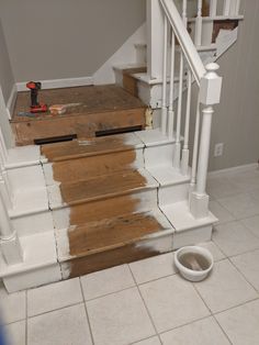 the stairs in this house are being painted white with brown stains on them and there is a dog bowl next to it