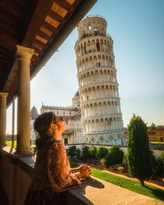 a woman looking at the leaning tower of pisa in italy, on a sunny day