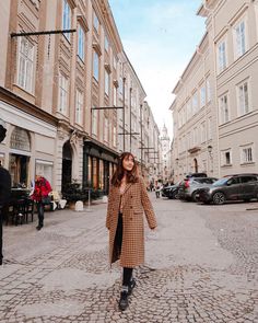 a woman standing in the middle of a cobblestone street