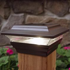 a light that is on top of a wooden post in front of some pink flowers