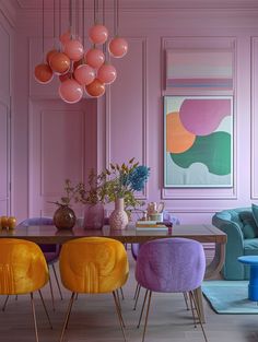 a dining room with pink walls and colorful chairs