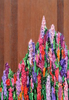 there are many colorful flowers in the vase on the wooden table with it's reflection