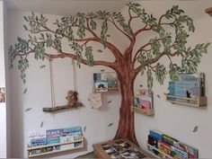 a child's room with a tree painted on the wall and bookshelves