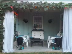 an outdoor patio with white chairs and curtains