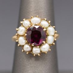 "Vintage Rhodolite Garnet and Seed Pearl Low Profile Cocktail Ring in 14 Yellow Gold This gorgeous mid-century delight features a sparkling round rhodolite garnet.  The stone measures approximately 8.3mm, calculating to approximately 2.39ct.  The stone is surrounded by lovely white seed pearls that measure about 3.5mm on average.  From front to back the ring measures just over 1/2\" in diameter.  It is crafted in solid 14k yellow gold and weighs 5.81g.  The ring is currently a size 6.25 and can Pearl Jewlery, Vintage Indian Jewelry, Gemstone Rings Vintage, Magic Witch, Wedding Vow, Edwardian Jewelry, Oc Inspo, Rings Vintage, Rhodolite Garnet