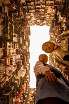 two people standing in front of a tall building with lots of buildings on the sides