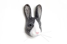 a black and white rabbit head mounted on a wall with one ear raised to the side