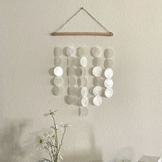 a vase filled with white flowers sitting next to a wind chime on top of a table