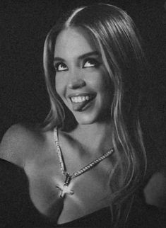 a black and white photo of a woman with long hair wearing a necklace smiling at the camera