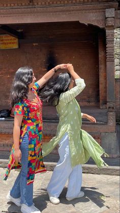 two women dancing in front of a building