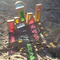 the letters are made out of wood and have colored paint on them in the sand