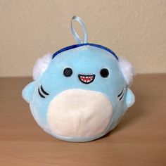 a blue stuffed animal with a smile on it's face sitting on a table