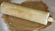 a wooden rolling pin sitting on top of a piece of wax paper next to some brown sugar