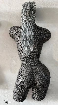 a black and white sculpture with chains on it's back, in the shape of a woman