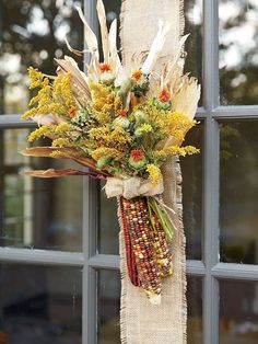 a bouquet of flowers hanging from the side of a window sill in front of a glass door