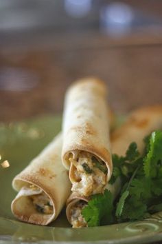 a green plate topped with two burritos and cilantro