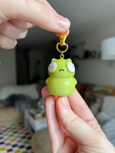 a person holding a green frog keychain in their hand