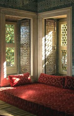 a red couch sitting in front of two windows