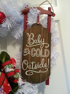 a wooden sign that says baby it's cold outside hanging on the front door