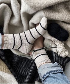 a person laying on top of a blanket with their feet up next to a ball of yarn