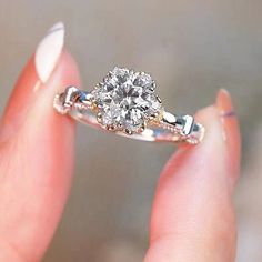 a woman's hand holding an engagement ring with a diamond in the center and two diamonds on each side