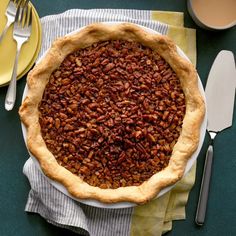 a pecan pie sitting on top of a table next to a fork and knife