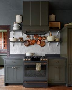 a kitchen with green cabinets and pots on the wall