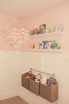 a baby's nursery with pink and white wallpaper, two baskets holding stuffed animals