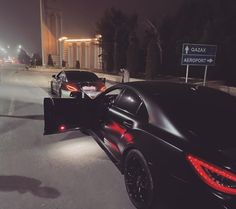 two cars are parked on the street at night