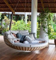 a person laying in a hanging chair on a wooden floor with the words outdoor porch bed above it