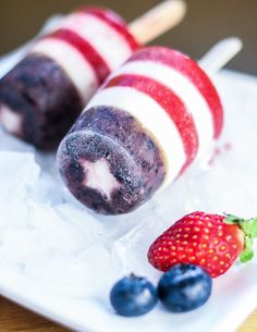 two popsicles with blueberries and strawberries on them