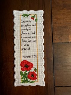 a cross stitch bookmark with an image of red flowers on it and the words charm is