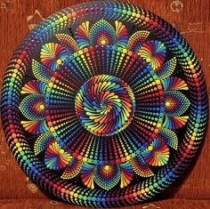 a colorful circular painting on a wooden surface