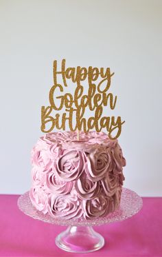 a birthday cake with pink frosting and gold glitter topper that says happy golden birthday