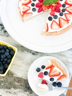 two plates with slices of cheesecake and berries on them