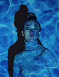 a woman standing in the water with her shadow projected on her face and body behind her