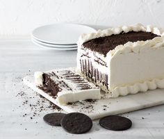 a chocolate cake with white frosting and oreo cookies on the side next to it