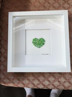 a white frame with a green heart in the middle on top of a brown table