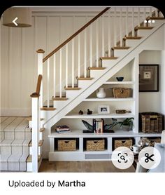 the stairs in this house are white and have baskets under them on each shelf below